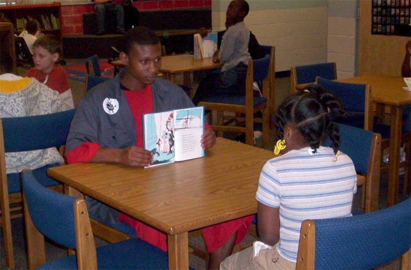Middle School Student Reads To Elementary Student