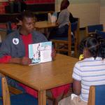 Middle School Student Reads To Elementary Student